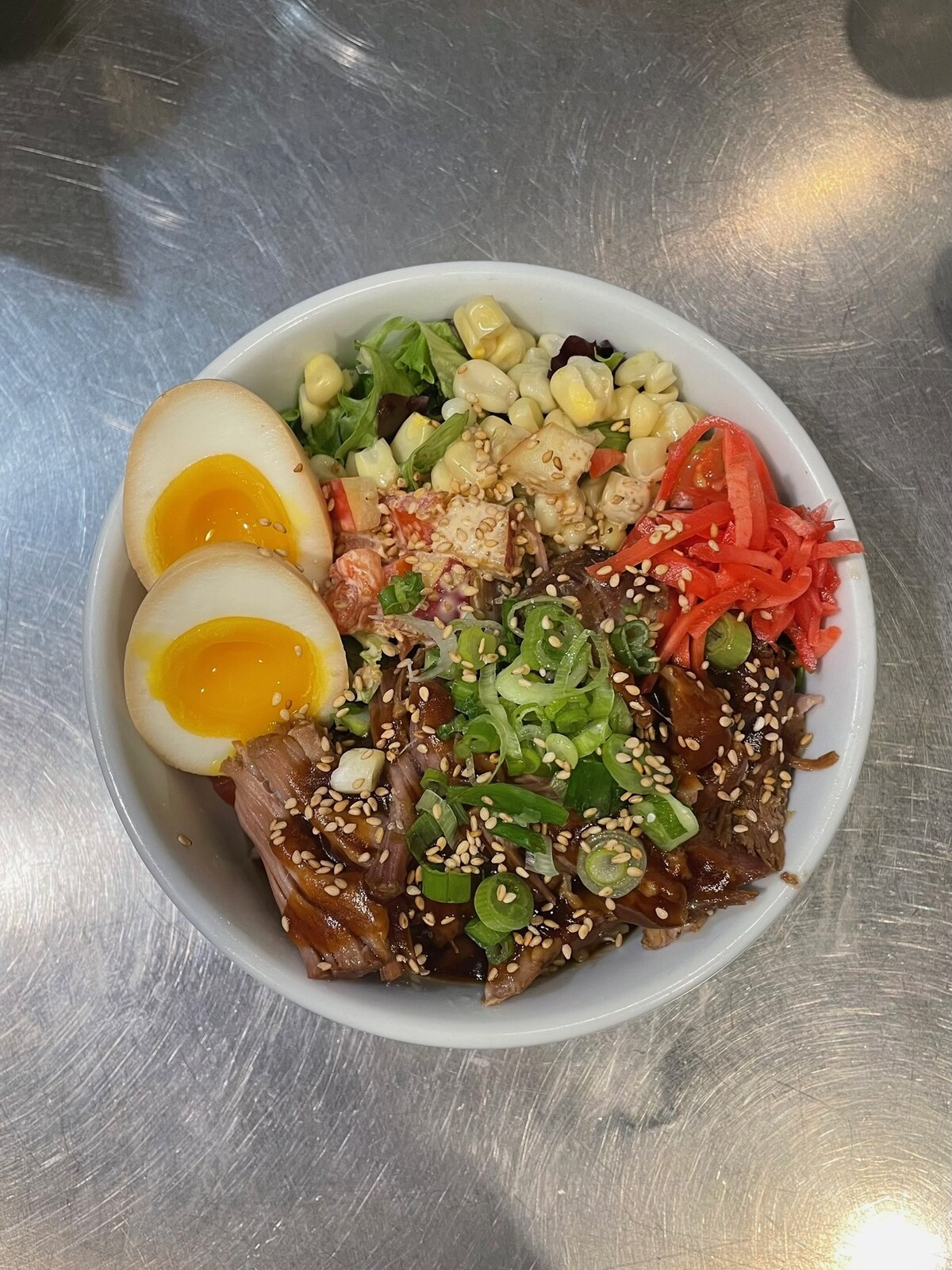 Chashu bowl with soft-boiled eggs, corn, tomato, and mixed greens