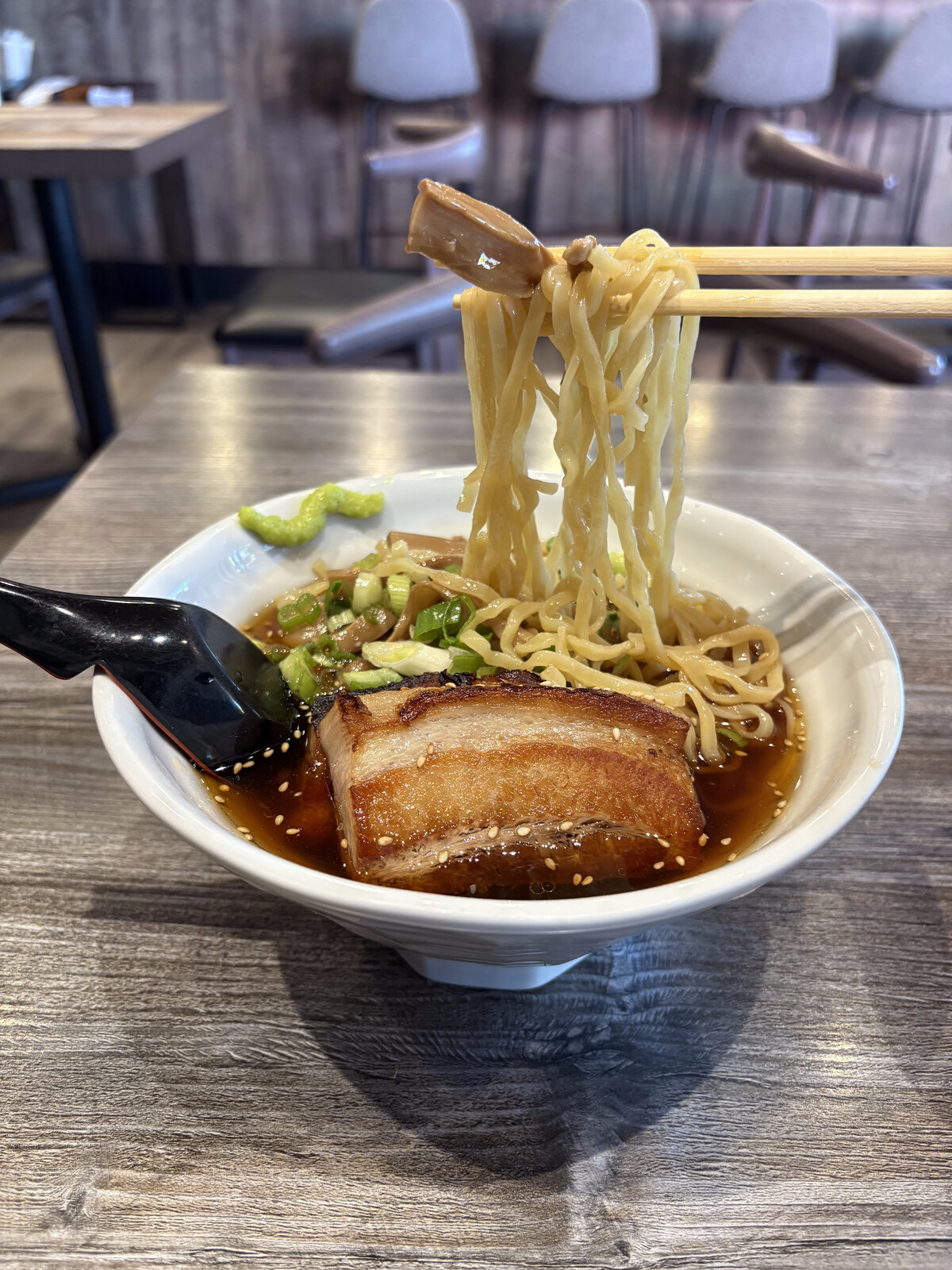 Shoyu ramen with chashu pork belly and noodles lifted with chopsticks